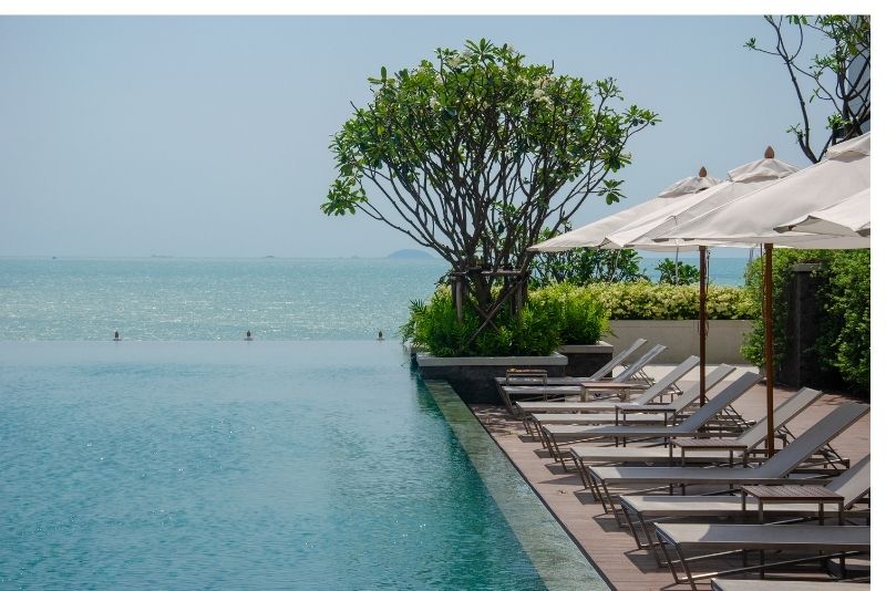 A pool with some resting chairs around it for relaxation. It is landscaped with concrete