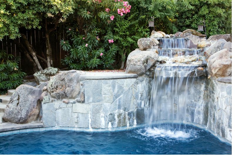 A waterfall is erected on the backyard and plenty of tree planted behind it
